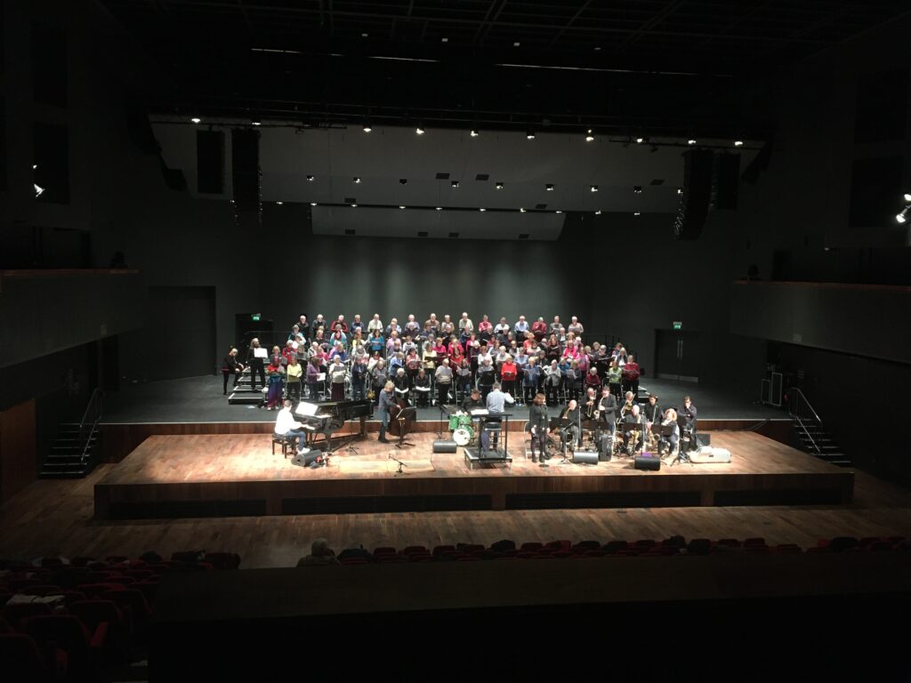 Wide shot photo of choir and band rehearsal at G-Live